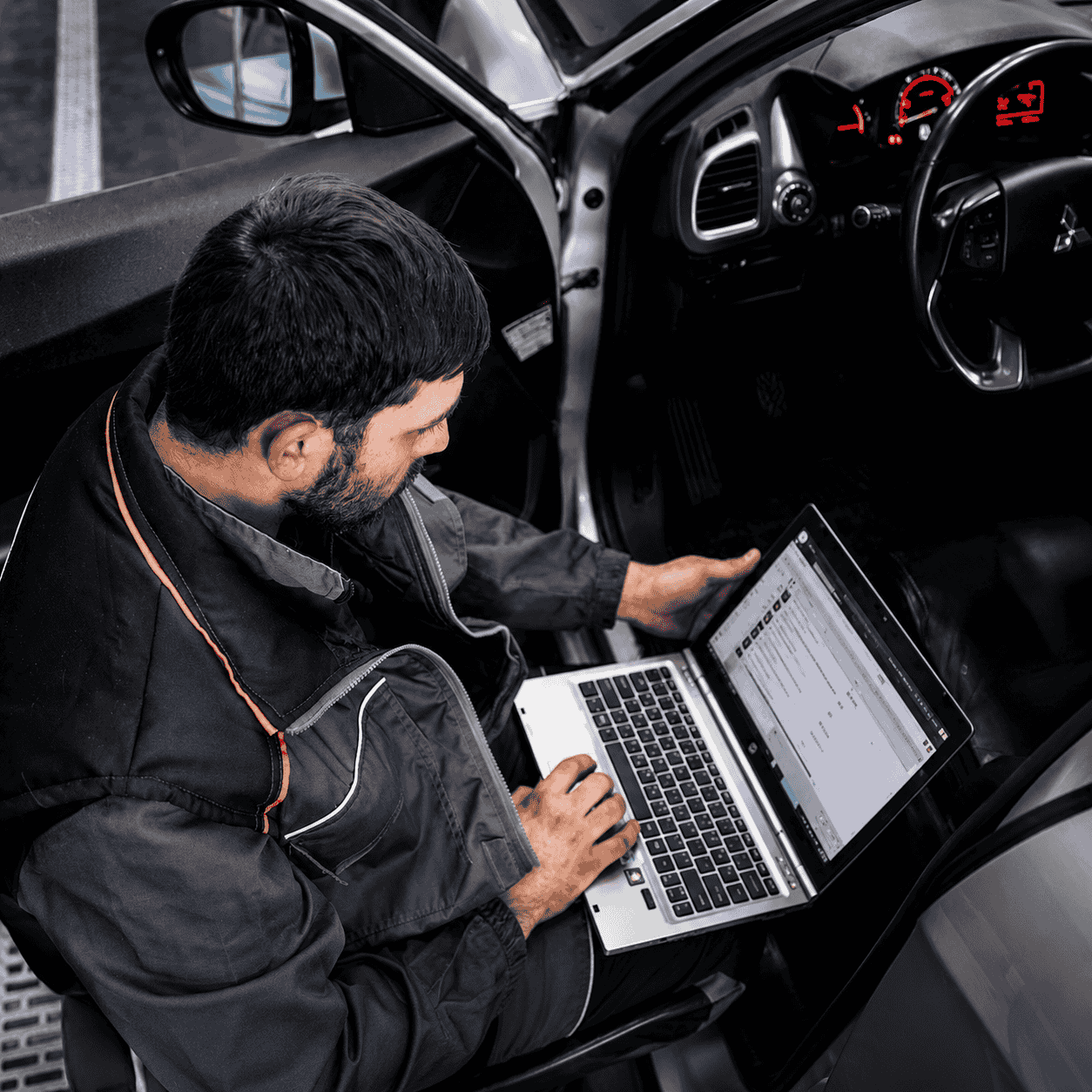 Mechaniker mit Diagnose-Laptop im Fahrzeug